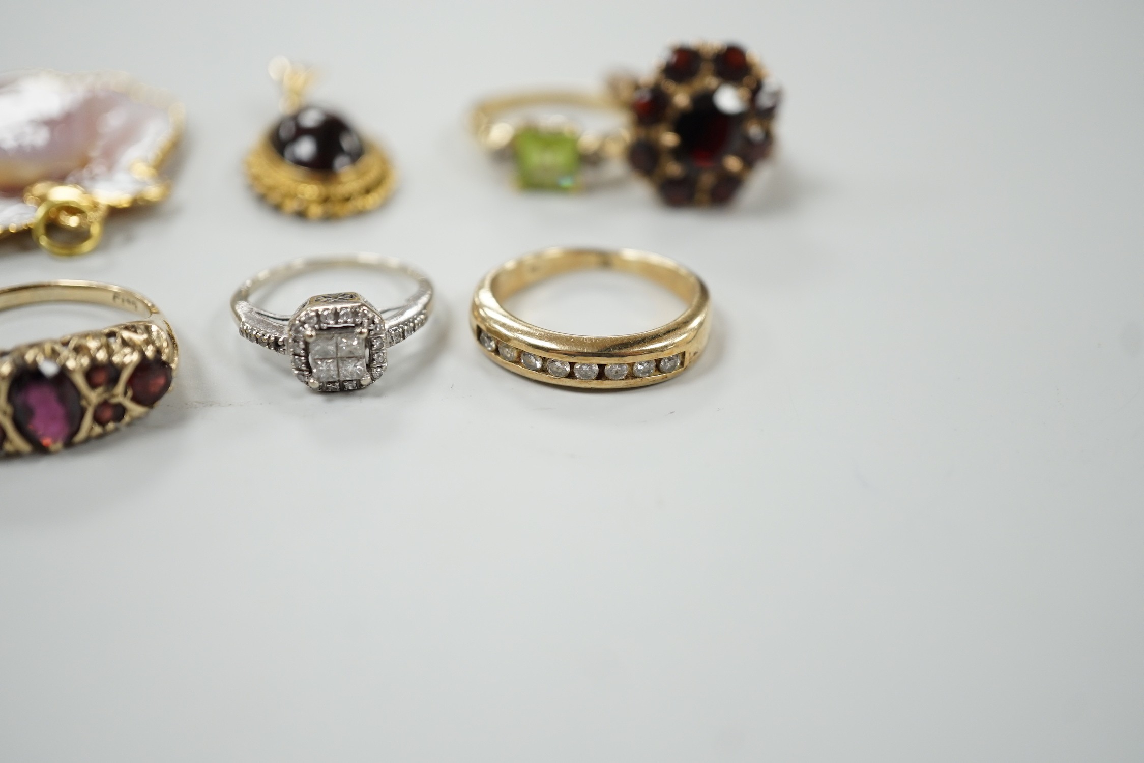 A 9ct and garner cluster set dress ring, size M, gross 4.9 grams, two yellow or white metal and diamond set rings, including half eternity and a yellow metal and garnet set half hoop ring, gross 8.8 grams, a 14k, single